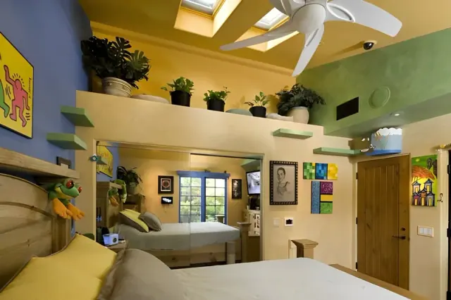 Bedroom with yellow bedding, green walls, elevated shelves, and a large mirror.