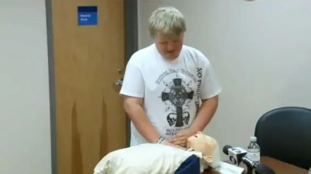 A boy practicing CPR on a training mannequin