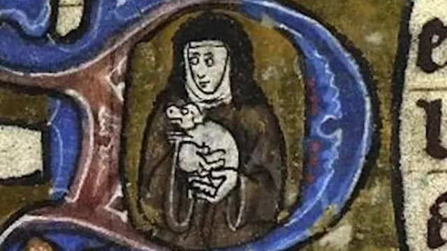 A robed figure holding a small dog in a decorated manuscript initial