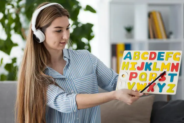 A woman wearing headphones and holding an alphabet chart, an illustrative stock image