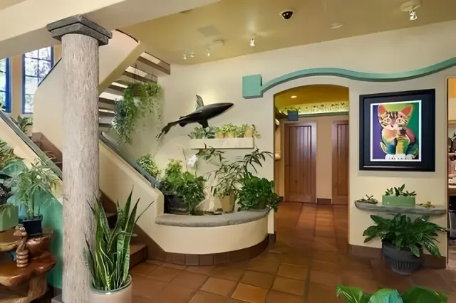 Hallway with a wrapped post, steps, plants, and a green walkway over a doorway.