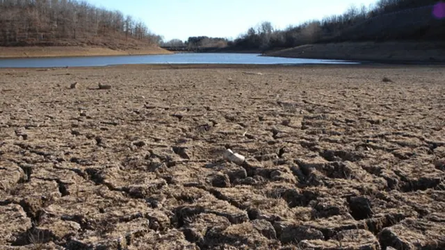 Cracked dry ground beside remaining water in an archive photograph