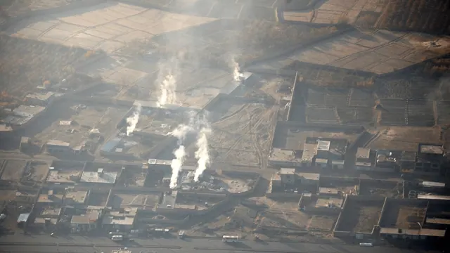 An archive aerial photograph of smoke rising from industrial buildings