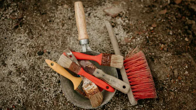 Brushes and small excavation tools on soil in an illustrative photograph