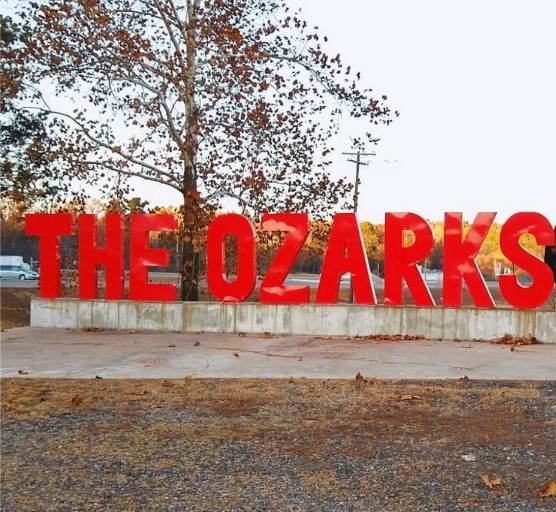 A sign reading The Ozarks in an illustrative regional photograph