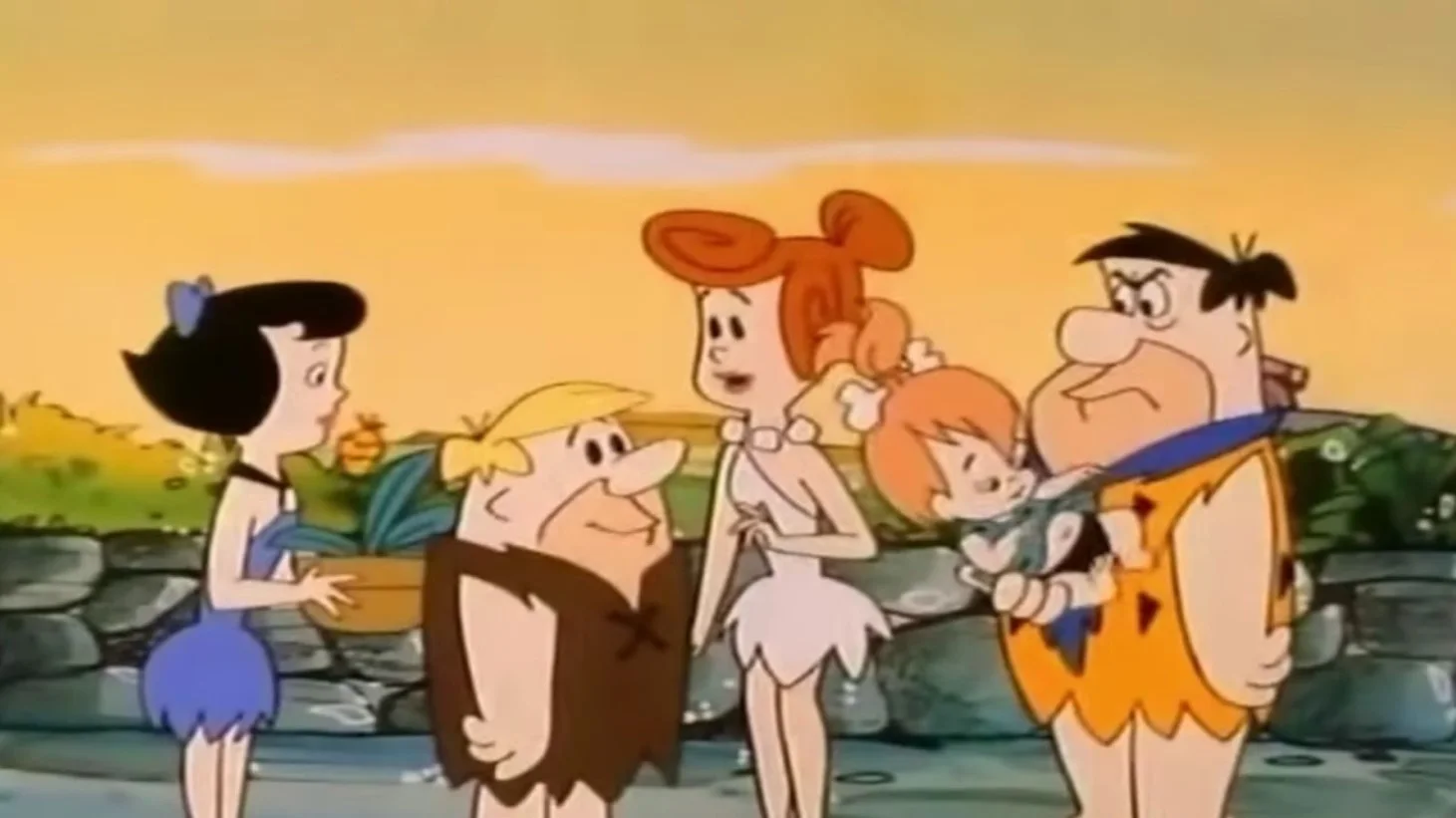 An image from the animated series "The Flintstones," showcasing the main characters including Fred, Wilma, Betty, and Barney, along with Pebbles and Bamm-Bamm.