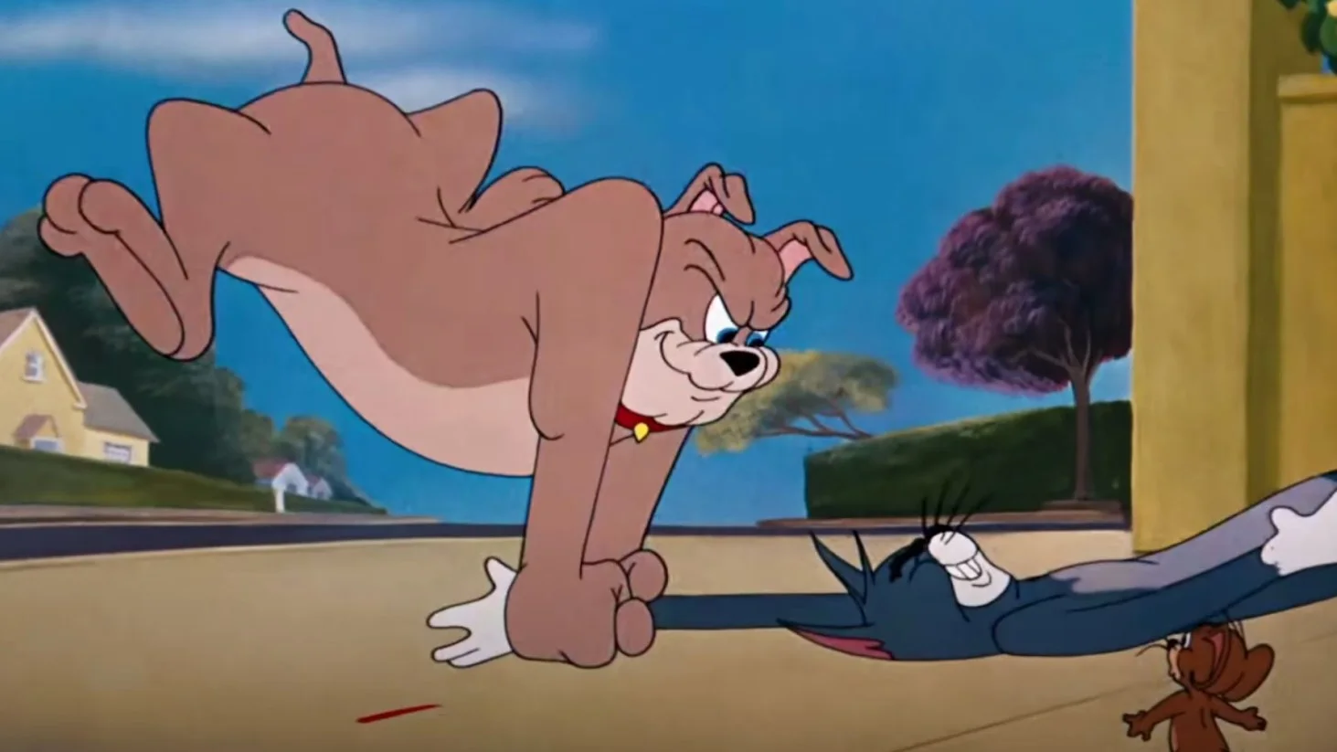 An animated image from "Tom and Jerry" showing Tom the cat being pursued by Spike the dog. In the foreground, Jerry the mouse watches the chase