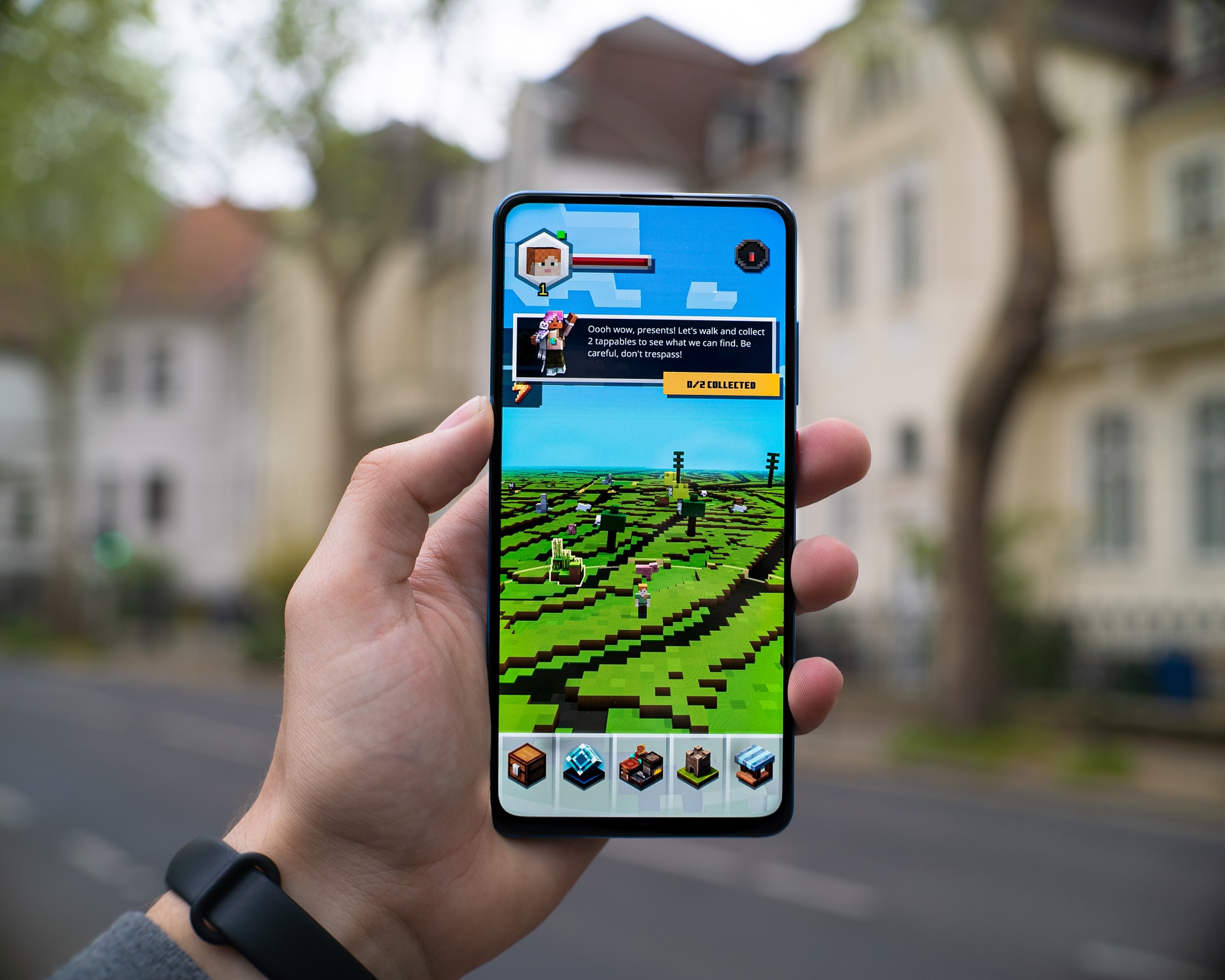 A hand holding a phone with a mobile game on its screen