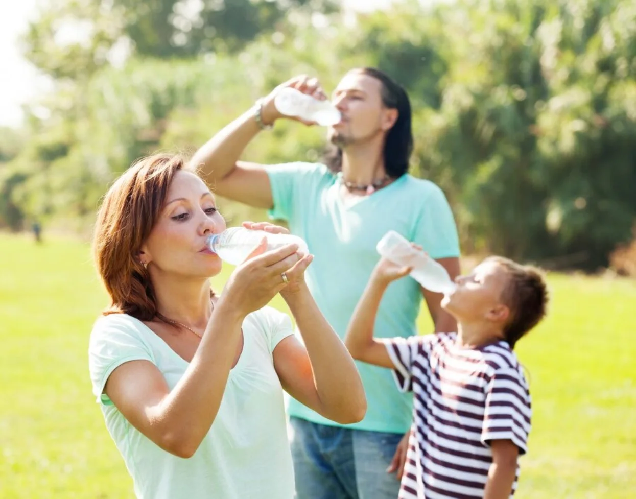 Mother, father, and son drinking water from plastic bottles