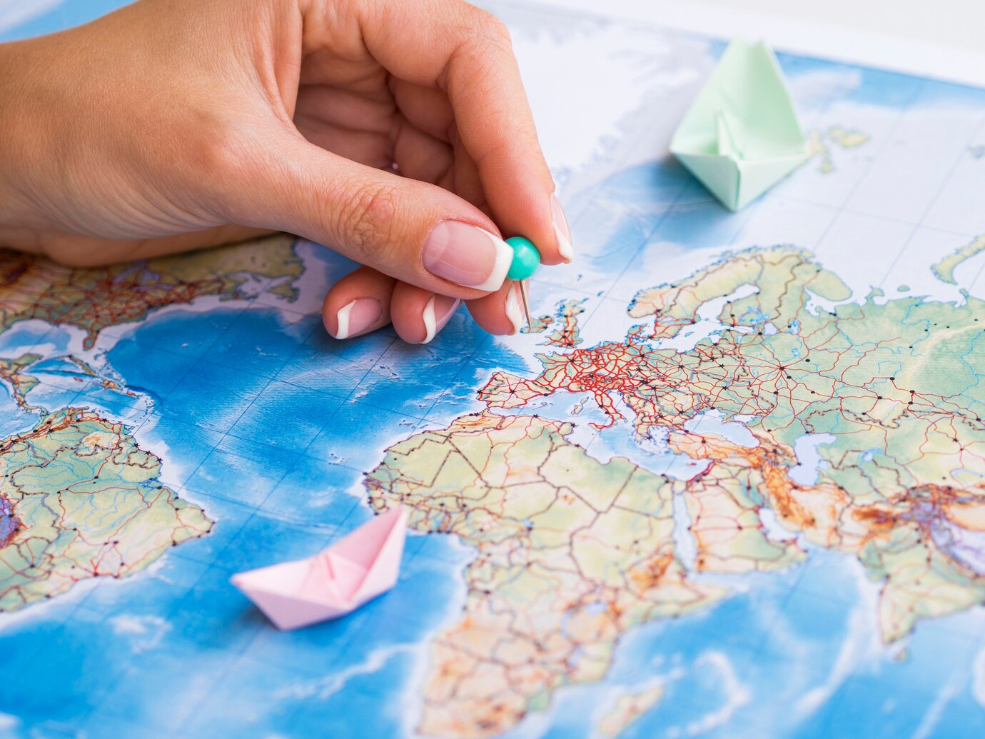 An illustrative photograph of paper boats and a pin on a map.