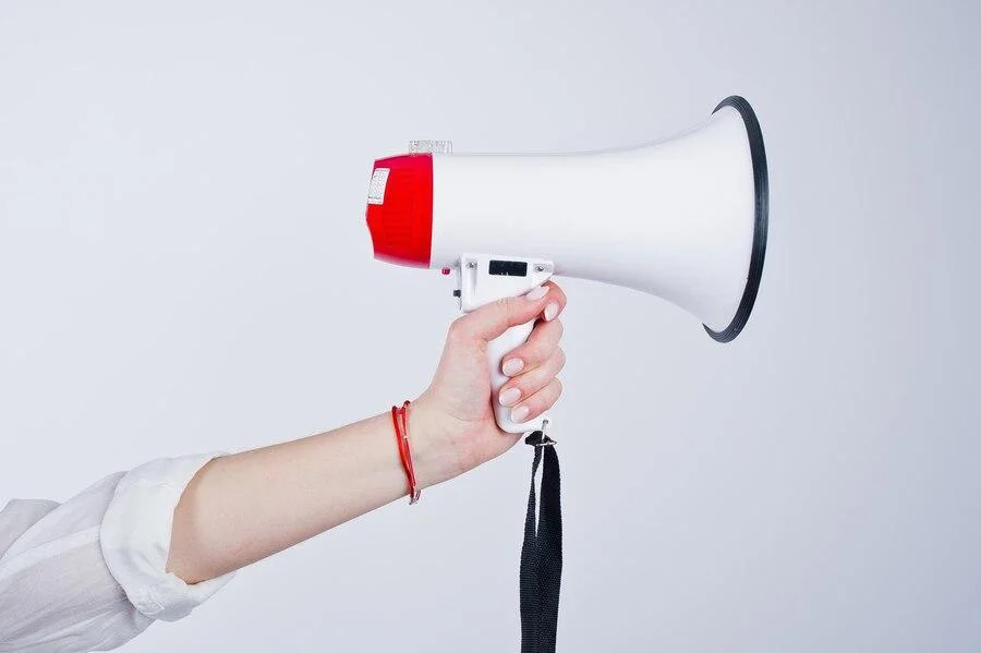 Hand holding a white and red megaphone
