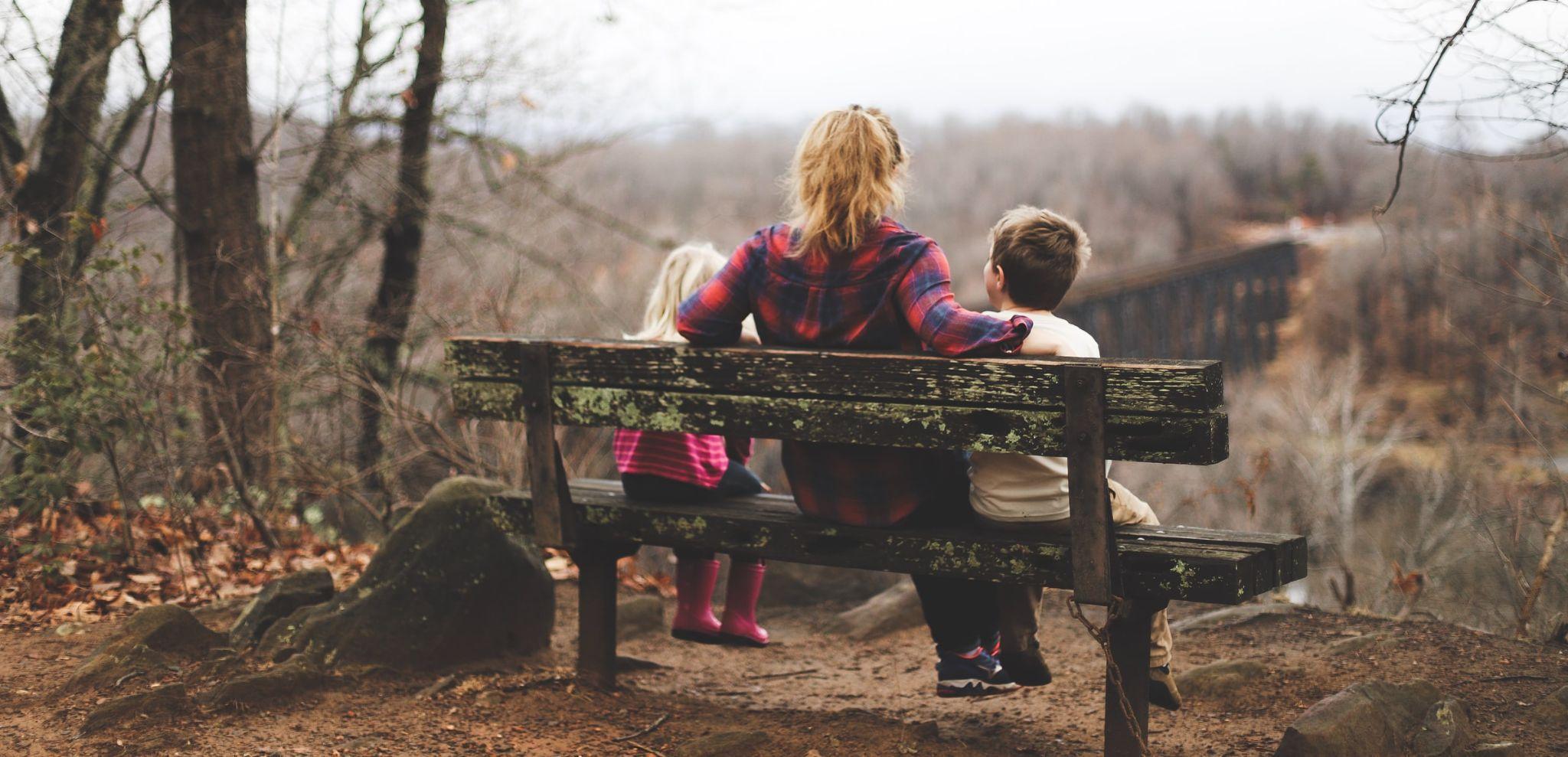 An adult and child sitting on a park bench