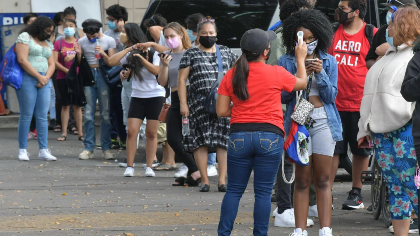 A line of high school students waiting in line for COVID temperature checks before entering school