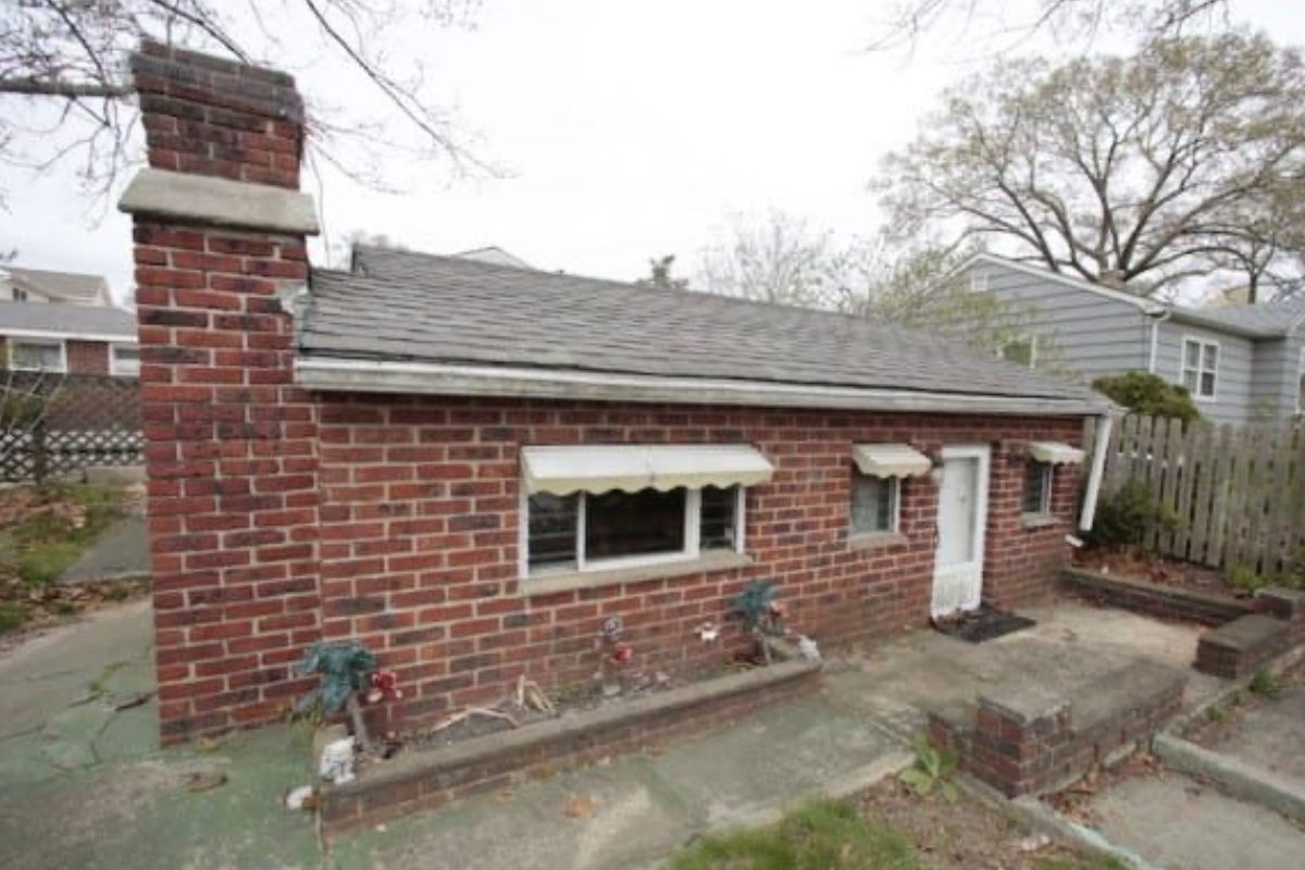 Exterior of the miniature brick cottage, with a small front door and windows.