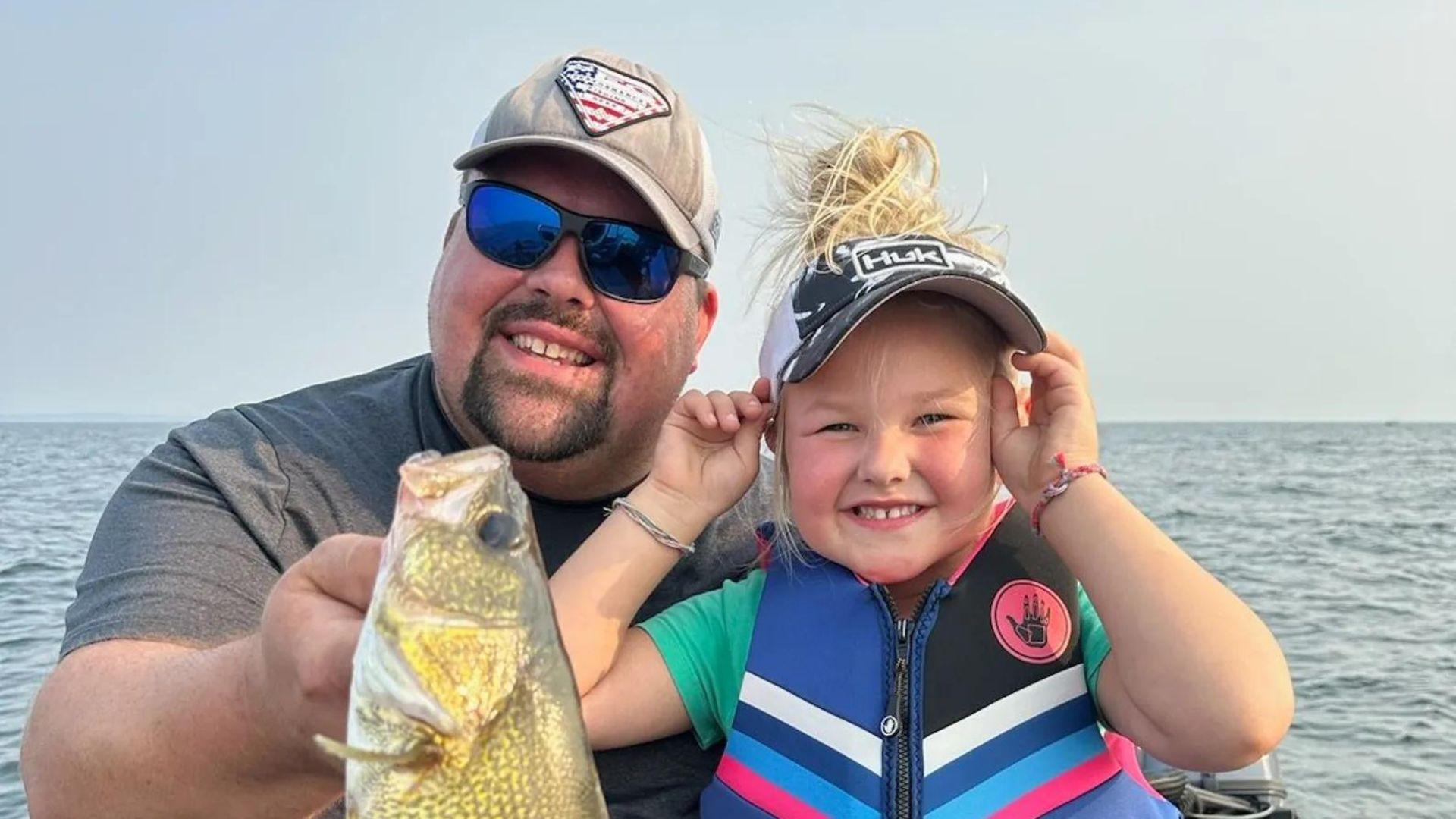 Tim and Henley Wollak on a boat holding a fish.