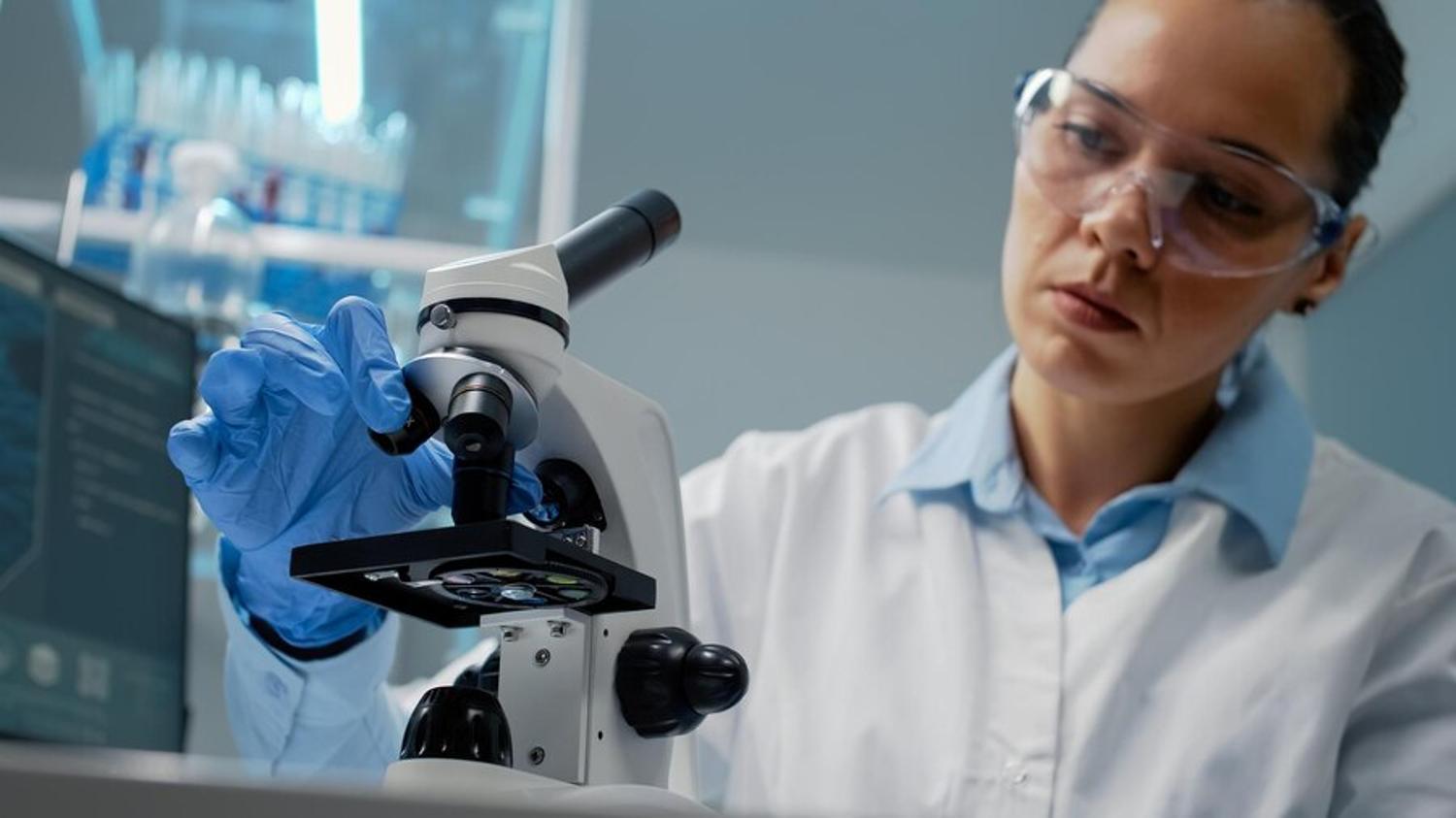 Illustrative laboratory photograph of a person using a microscope.