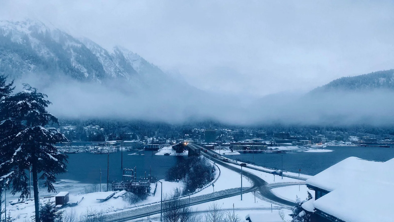 A tranquil winter scene of a lakeside town enveloped in snow and shrouded in mist