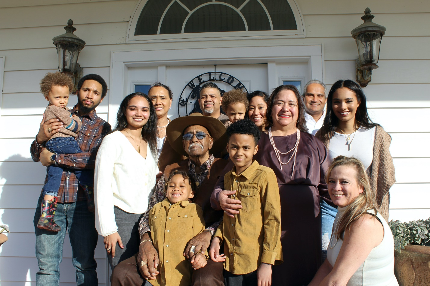 A multigenerational family posing outside a house