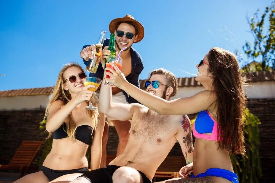 Friends smiling and drinking beer and cocktails in their bathing suits