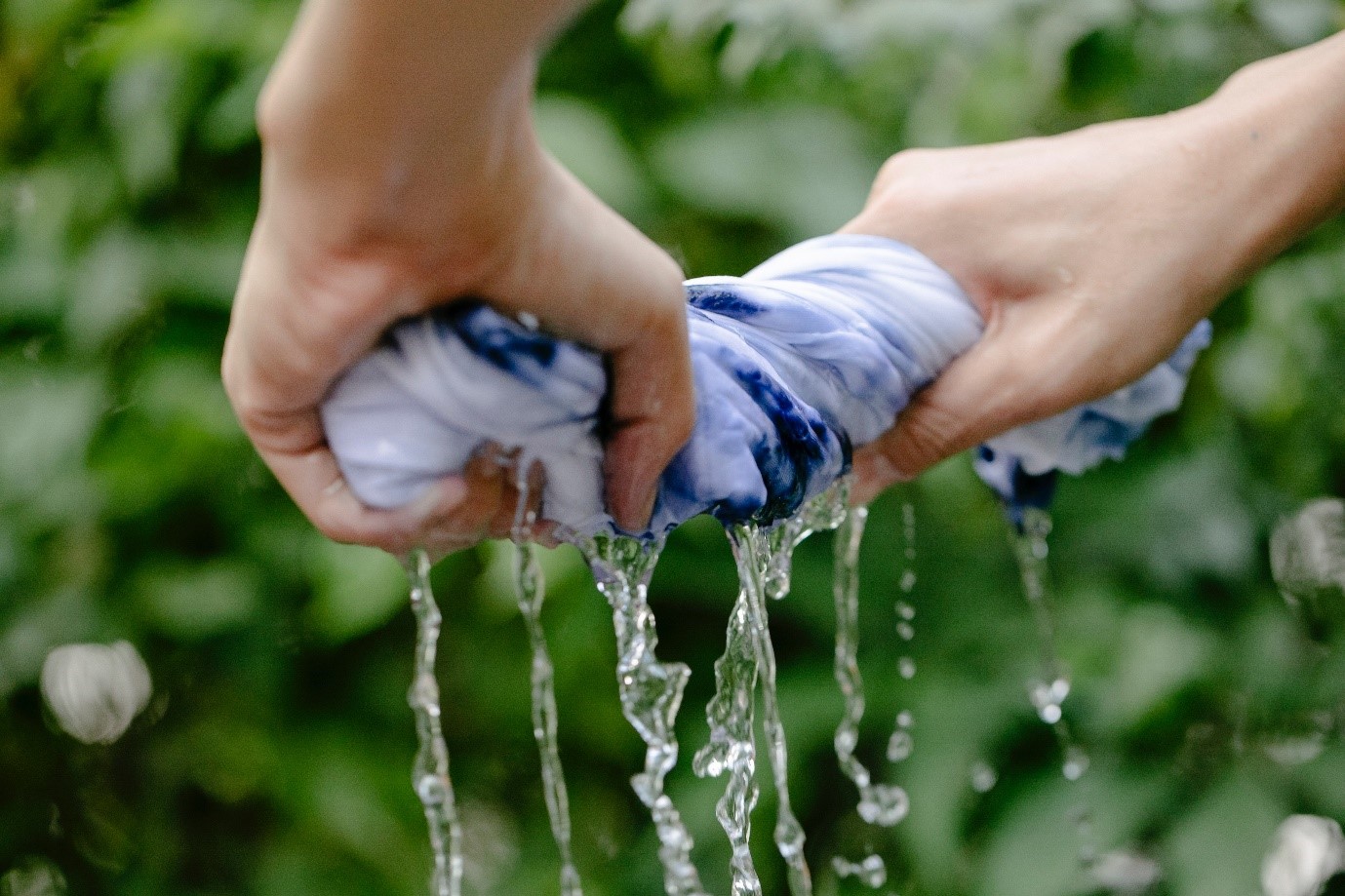 Hands wringing water from a piece of fabric outdoors