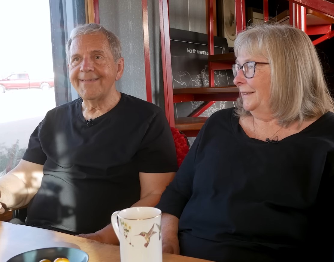 Clayton and Teresa sitting together at a table inside their mobile home.
