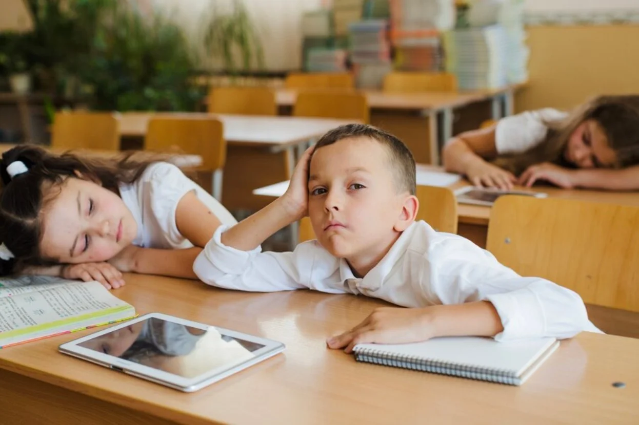 Young children in school falling asleep at their desks