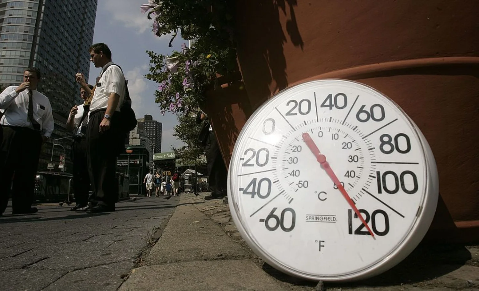 A thermometer in the sun on the sidewalk indicates a temperature of 120 degrees Fahrenheit