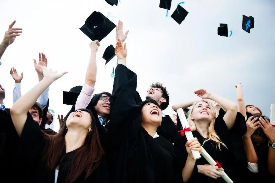 Graduates smiling and throwing their caps into the air in celebration