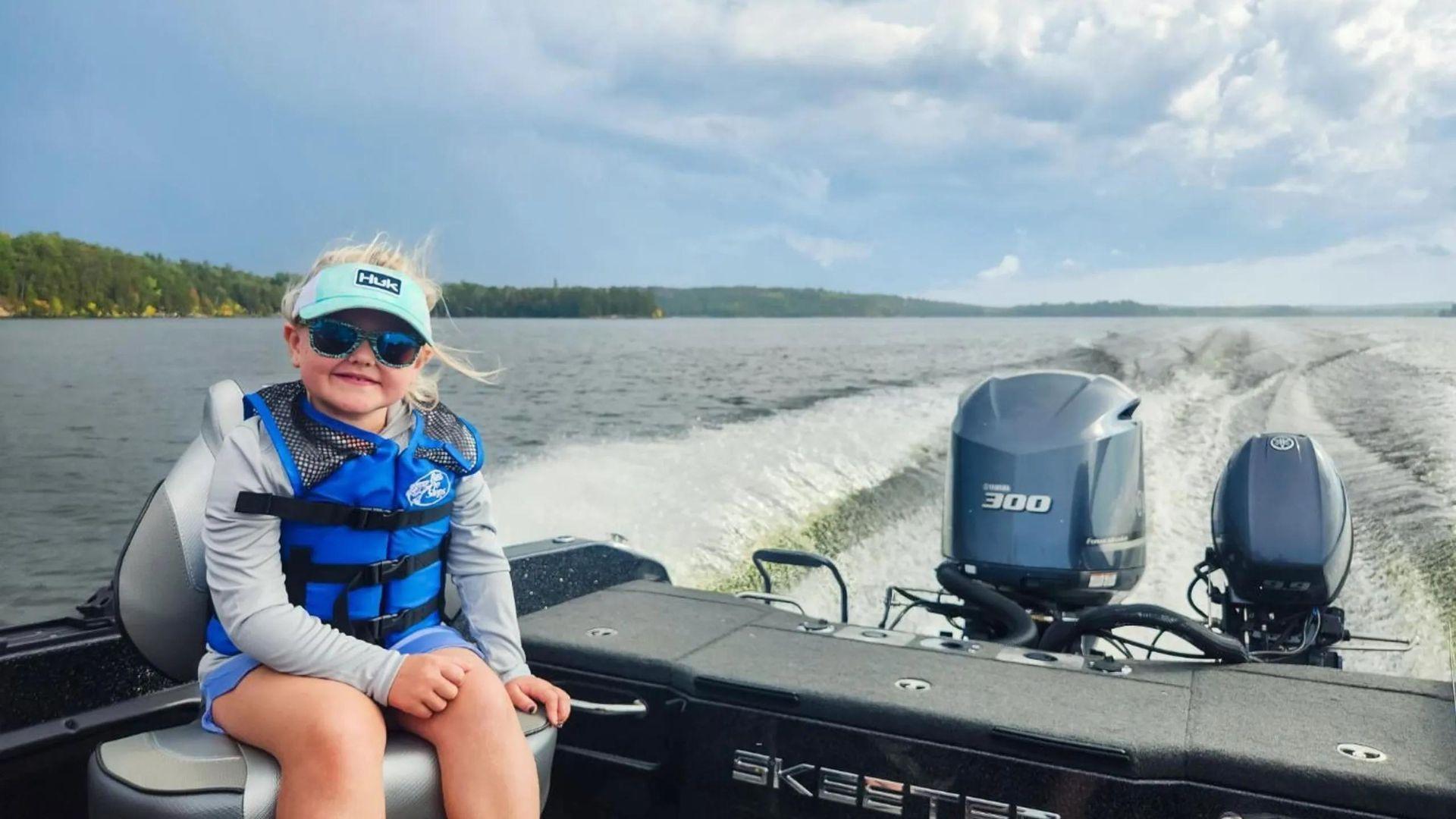 Henley Wollak wearing a blue life jacket and sunglasses aboard a boat.