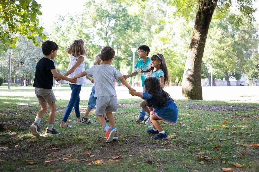 Children holding hands and playing outside in a park