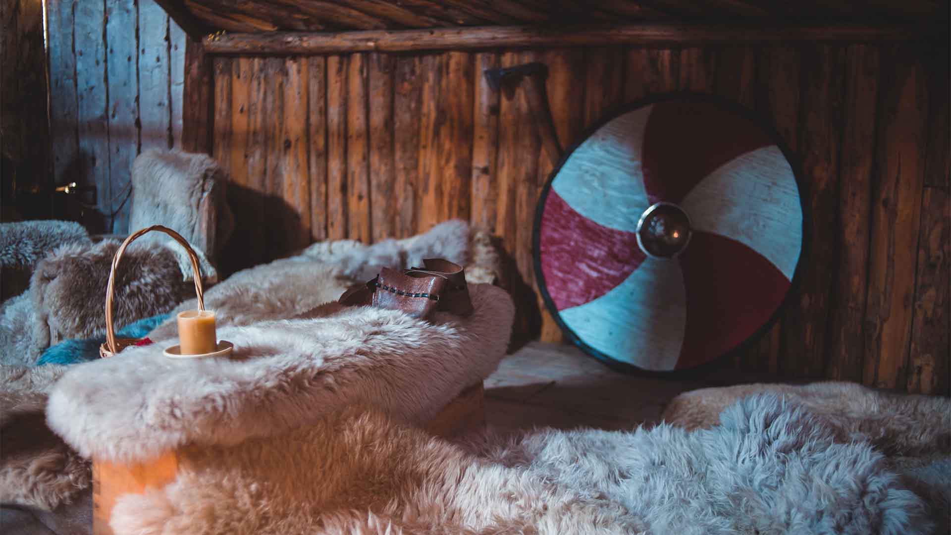 Illustrative photograph of a room furnished with hides and a round shield.