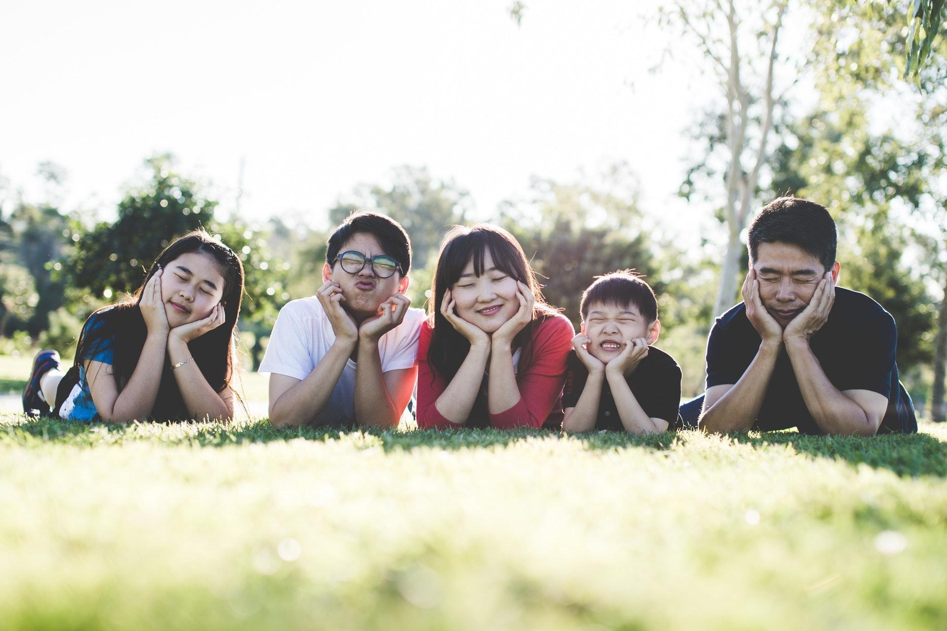 Five family members lying together on grass