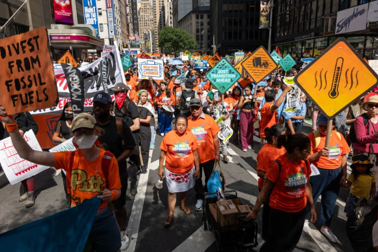 Climate change activists walk up the street in New York with orange signs